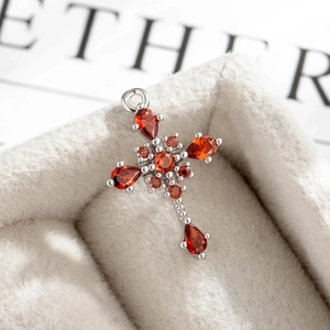 Luxurious silver cross pendant with red gemstones displayed in a beige velvet jewelry box