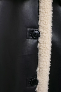 Detail shot of black leather and beige faux fur texture with round button closure