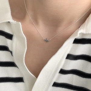 Detail of 925 sterling silver bird charm choker worn on a minimalist collarbone chain