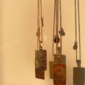 Macro detail of gold zodiac pendant necklaces featuring Aquarius and Libra engravings