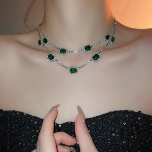 Nahaufnahme einer zweilagigen Silberkette mit smaragdgrünen Steinen und Diamanten am Model