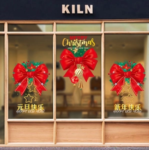 Detail of red festive bows with gold stars and pine needles on glass window sticker