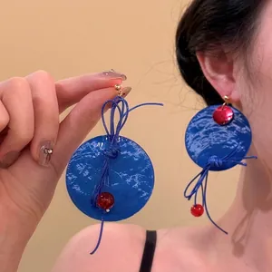 Detail of bohemian drop earrings with blue marbled resin and red bead accents