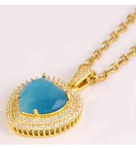 Macro detail of heart blue topaz pendant with white moissanite halo on gold chain