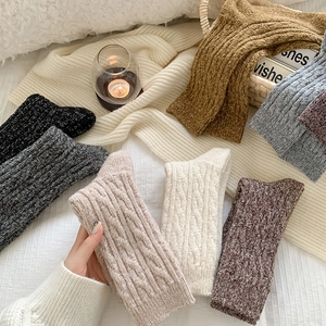 Chunky knit wool socks in neutral tones arranged on a cozy, warm lifestyle background