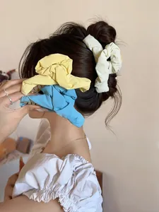 Detailed view of colorful pleated fabric hair scrunchies set in yellow blue and beige