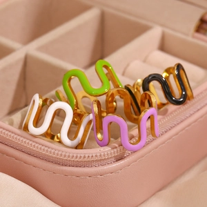 Macro view of wave-shaped 18K gold-plated rings with colorful enamel in a pink jewelry box