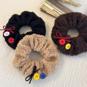 Détail de chouchous en peluche imitation laine avec boutons décoratifs et petits nœuds