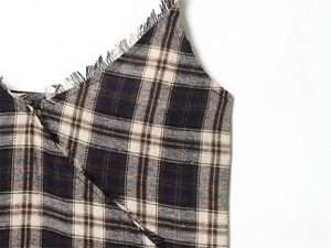 Detailed macro view of the brown plaid fabric texture with fringe edges on the dress