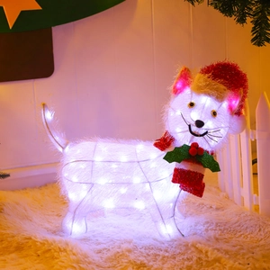 Close-up of lighted Christmas cat figure with red hat and scarf on a warm indoor porch