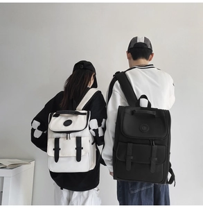 Two people wearing black and white minimalist nylon backpacks in a clean studio setting