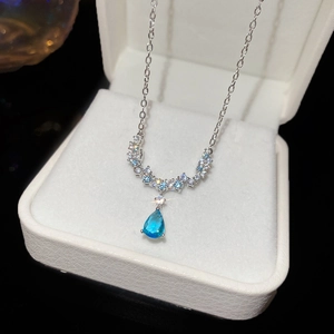 Close-up of a silver necklace with a blue teardrop pendant in a luxury jewelry box
