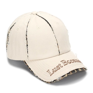 Détail de la casquette blanc cassé avec bords effilochés, imprimé léopard et broderie