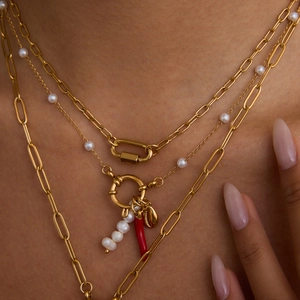 Detalle de collares a capas bañados en oro de 18K con perlas y colgante de chile rojo