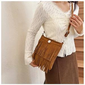 Brown suede crossbody bag with fringe detailing and silver logo buckle on a female model