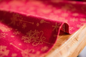 Macro detail of red cotton linen Christmas tablecloth with gold snowflake patterns