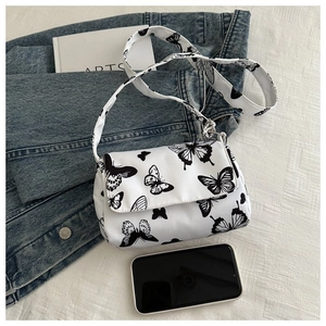 Close-up of white flap shoulder bag with black butterfly prints and silver hardware