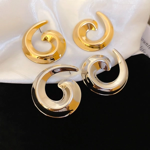 Macro view of polished gold and silver snail spiral earrings with reflective metal finish
