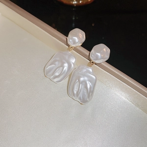 Dettaglio di orecchini di perle barocche irregolari con maglie dorate su seta lucida