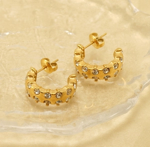 Macro view of C-shaped 18K gold-plated hoop earrings with double row of rhinestones
