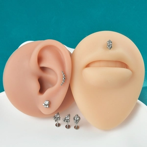 Detailed display of titanium labret studs and curved barbell on silicone ear and lip models