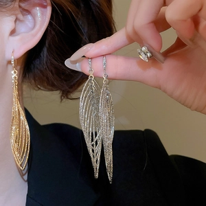 Détail de boucles d'oreilles pendantes dorées avec design feuille et cristaux brillants