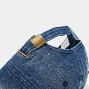Detailed close-up of dark blue denim baseball cap with vintage brass adjustable buckle