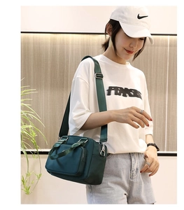 Fashionable dark green nylon crossbody bag with adjustable straps shown on a model