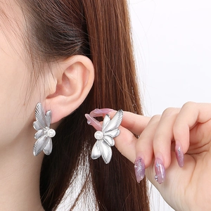 Silver butterfly wing earrings with white pearls shown on a model for scale and style