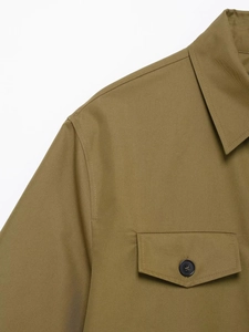 Detailed close-up of khaki shirt collar and flap pocket with black button and twill texture