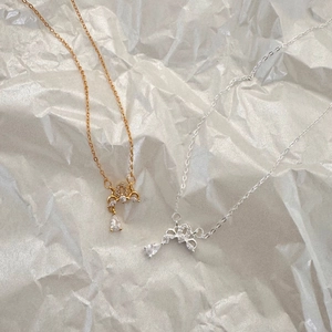 Detail of gold and silver bow necklaces with sparkling cubic zirconia on a gray surface