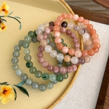 Close-up of colorful gemstone bead bracelets with jade gourds in a decorative tray