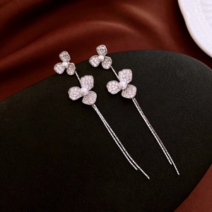 Boucles d'oreilles fleurs à pompons argentés avec zircons et perles sur support noir