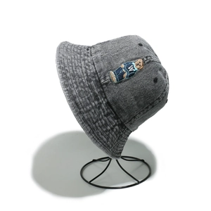 Detailed close-up of grey washed denim bucket hat featuring an embroidered bear patch