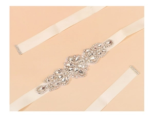 Detailed view of hand-sewn crystal bridal belt with rhinestone floral patterns on beige ribbon