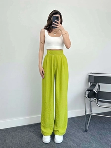 Détail du pantalon large taille haute vert herbe avec texture de tissu drapé élégant