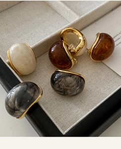 Macro shot of resin oval stud earrings with 18k gold plating and marble texture finish