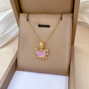 Détail du pendentif papillon rose avec chaîne dorée dans un coffret cadeau chic
