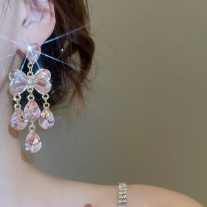Gros plan de boucles d'oreilles nœud en cristal rose étincelant avec pompons