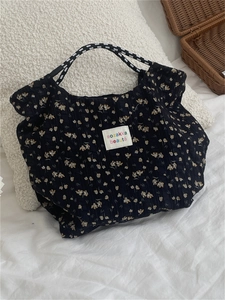 Detail of floral quilted tote bag featuring braided rope handles and woven brand label