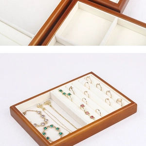 Detail of wooden jewelry tray with ring slots and cream velvet lining showing storage usage