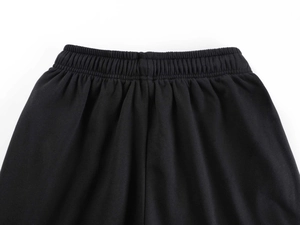 Detailed close-up of the elastic waistband and knit texture on black wide-leg joggers