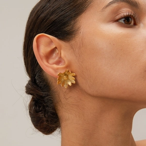 Detailed close-up of 18k gold plated stainless steel daisy flower stud earring on model