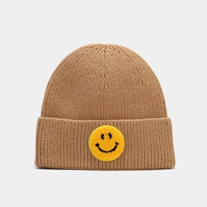 Gros plan sur la maille côtelée marron et l'écusson brodé d'un smiley jaune vif