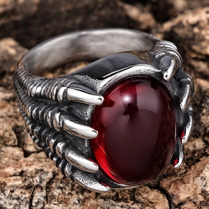Vintage gothic dragon claw ring with large oval red gemstone on rustic wood background