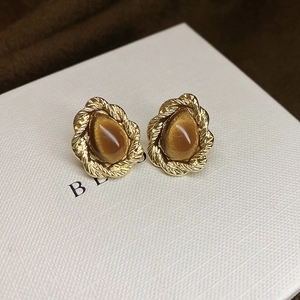 Detailed macro of gold twisted metal frame with teardrop brown tiger eye gemstone