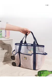 Close-up of white mesh beach bag with navy handles and BEACH LOVE patch detail