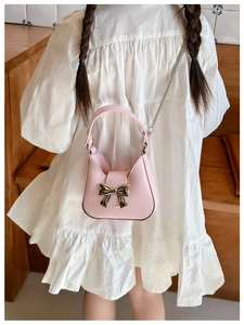 Detail of pink PU leather crossbody bag with metal bow and silver chain strap