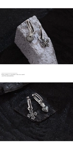 Macro detail of gothic silver hoop earrings with black zircon heart and cross pendants