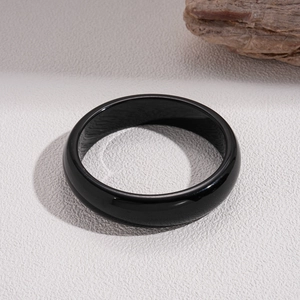 Close-up of minimalist black resin geometric round bangle with polished obsidian-like finish